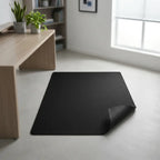 Tapis de bureau noir 90x120 cm posé sur sol gris 
dans un bureau minimaliste en bois – ErgoStudio
